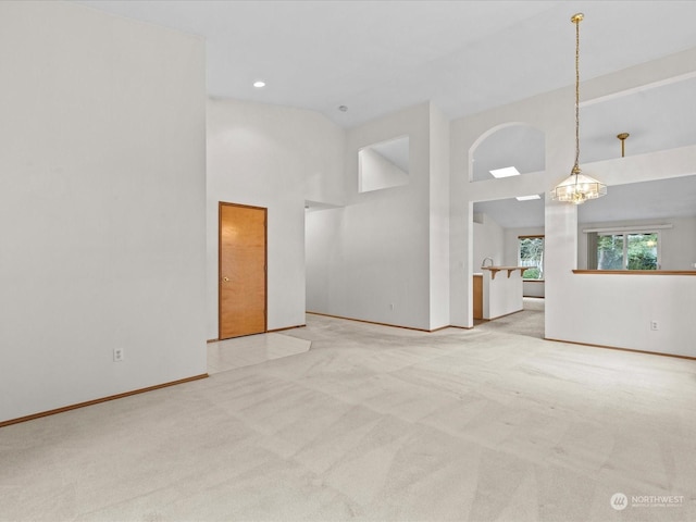 unfurnished room with light carpet, a notable chandelier, and high vaulted ceiling