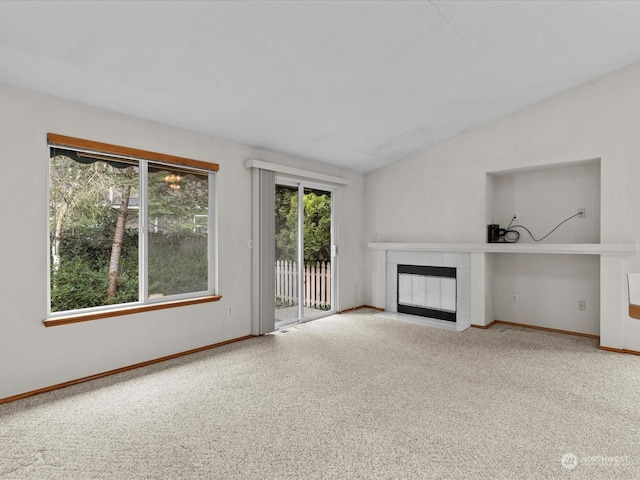 unfurnished living room with lofted ceiling, a fireplace, and carpet floors