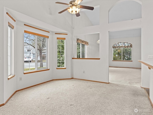 carpeted empty room featuring plenty of natural light, high vaulted ceiling, and ceiling fan