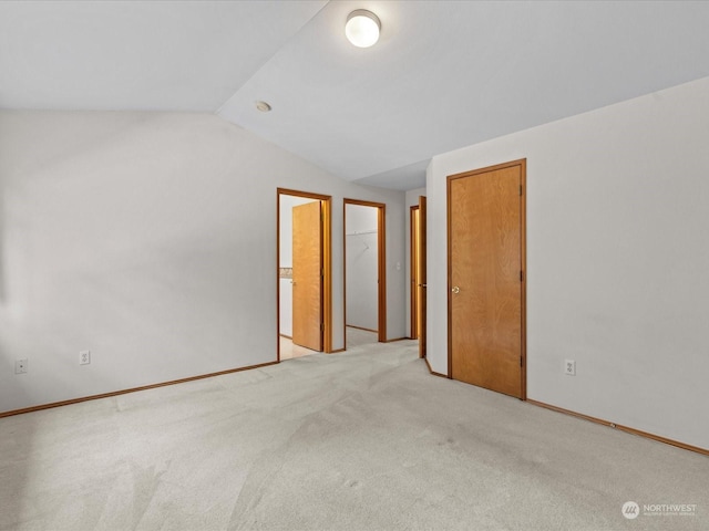 carpeted empty room with vaulted ceiling