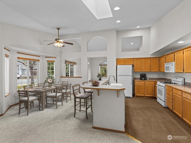 kitchen with a kitchen bar, sink, high vaulted ceiling, dark carpet, and white appliances