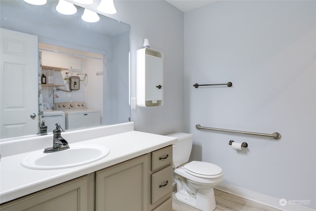 bathroom featuring hardwood / wood-style flooring, washing machine and dryer, vanity, and toilet