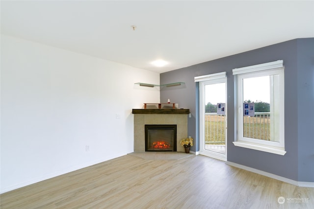 unfurnished living room with a tiled fireplace and light hardwood / wood-style flooring