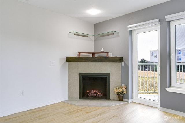 unfurnished living room with a tiled fireplace and light wood-type flooring