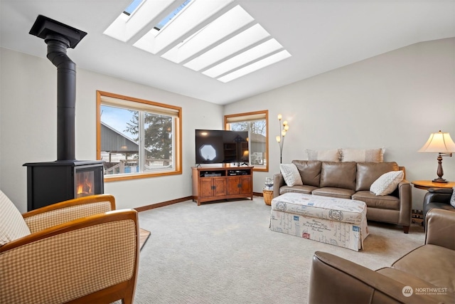 living room featuring light colored carpet, lofted ceiling with skylight, and a wood stove