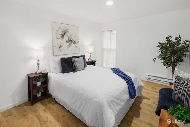 bedroom with a baseboard heating unit and light wood-type flooring