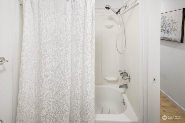 bathroom with shower / bathtub combination with curtain and hardwood / wood-style flooring