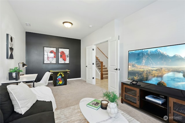 living room with stairway, baseboards, visible vents, and light colored carpet