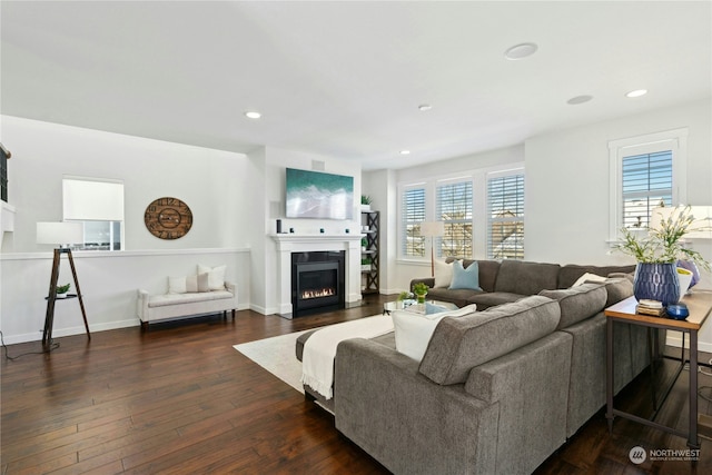 living area with dark wood-type flooring, a glass covered fireplace, baseboards, and recessed lighting