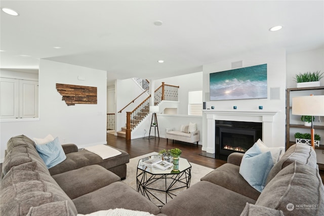 living area featuring dark wood-type flooring, stairway, a glass covered fireplace, and recessed lighting