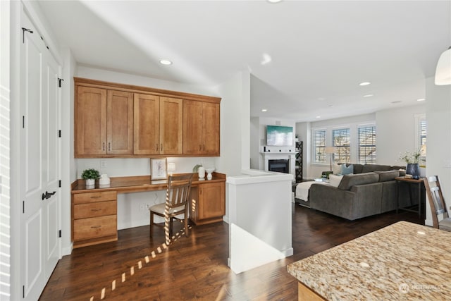 kitchen with dark wood finished floors, built in study area, open floor plan, a fireplace, and recessed lighting