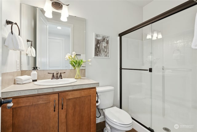 bathroom with a stall shower, vanity, and toilet