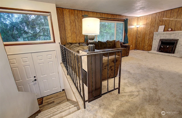 carpeted living room with a brick fireplace, a textured ceiling, and wood walls