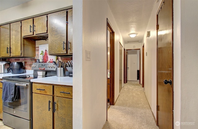 kitchen featuring tasteful backsplash, stainless steel electric range, and light colored carpet