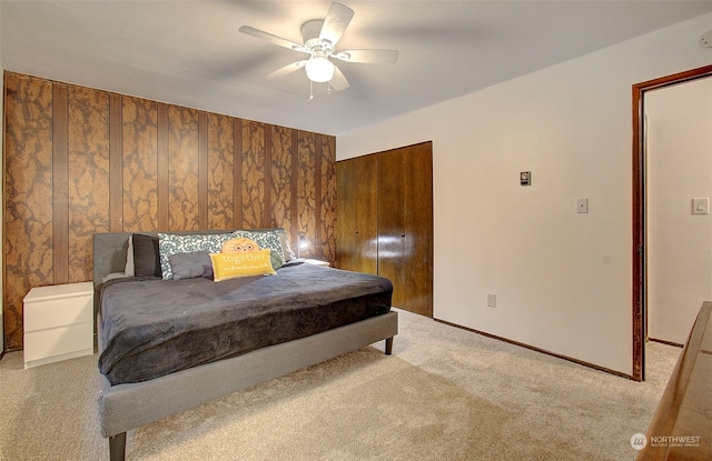 bedroom featuring ceiling fan, wooden walls, and light carpet