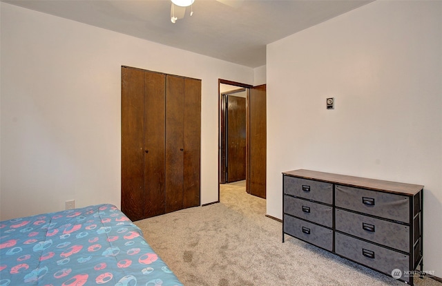 bedroom with ceiling fan, light colored carpet, and a closet