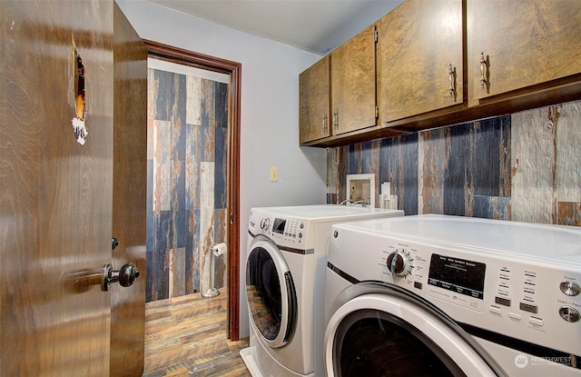 laundry room featuring cabinets, wood-type flooring, and washer and clothes dryer