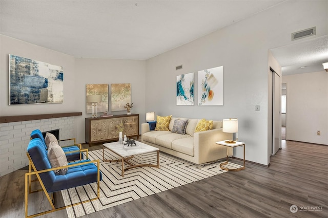 living room featuring wood-type flooring and a brick fireplace