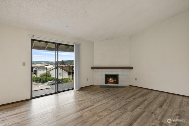 unfurnished living room featuring a brick fireplace, hardwood / wood-style floors, and a textured ceiling