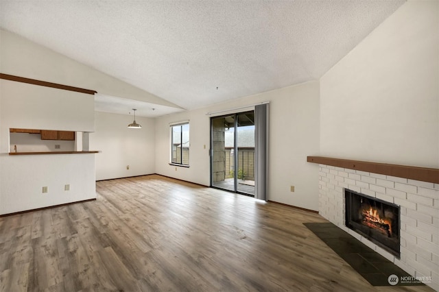 unfurnished living room featuring hardwood / wood-style floors, a fireplace, a textured ceiling, and vaulted ceiling