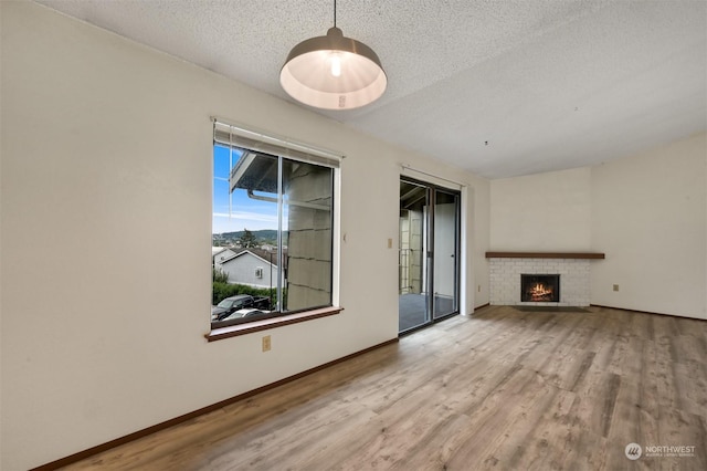 unfurnished living room featuring a fireplace, light hardwood / wood-style flooring, and a textured ceiling