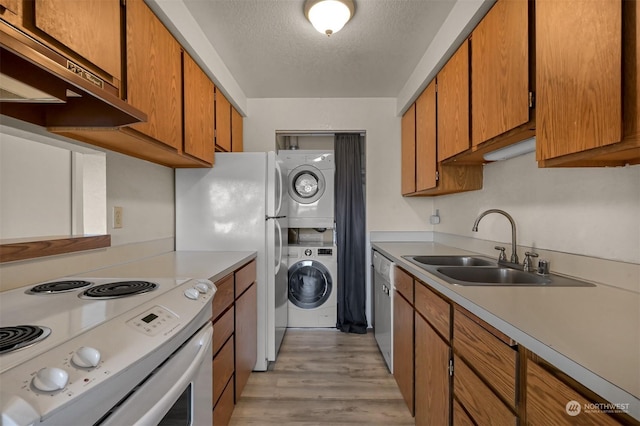 kitchen featuring stacked washer and dryer, sink, electric range, a textured ceiling, and stainless steel dishwasher