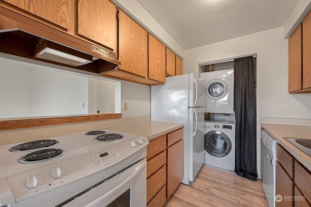 kitchen with sink, white appliances, stacked washer and clothes dryer, light hardwood / wood-style floors, and a textured ceiling