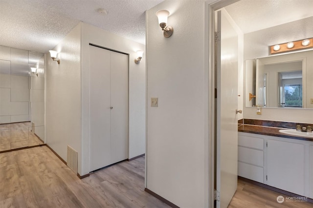 bathroom with hardwood / wood-style flooring, vanity, and a textured ceiling