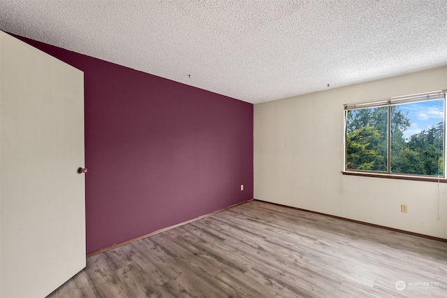 empty room featuring a textured ceiling and light wood-type flooring