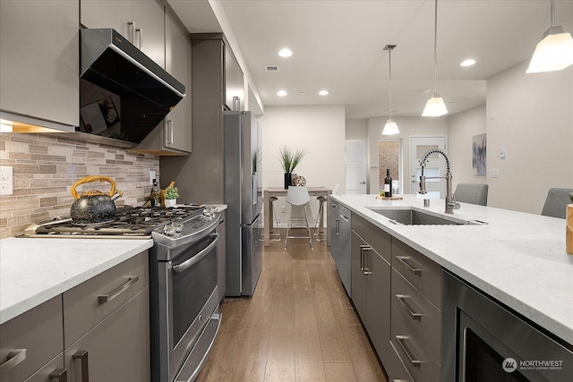 kitchen with appliances with stainless steel finishes, sink, gray cabinetry, dark hardwood / wood-style flooring, and hanging light fixtures