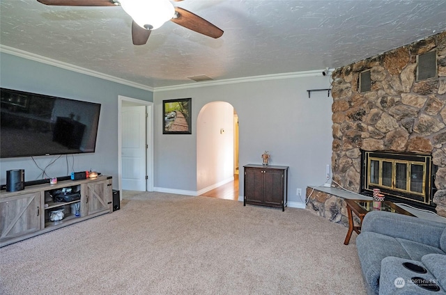 living room featuring crown molding, a textured ceiling, ceiling fan, light colored carpet, and a fireplace