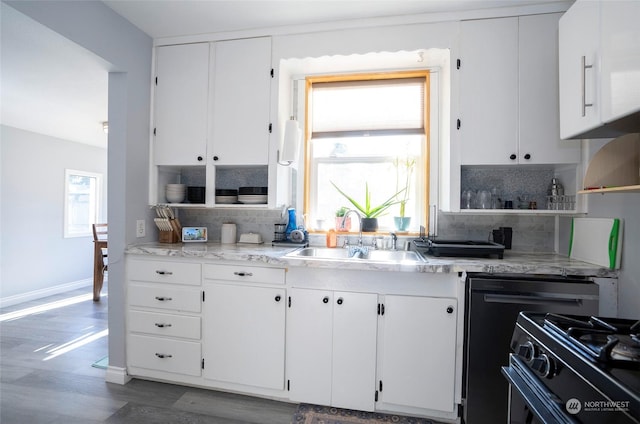 kitchen featuring sink, black gas range oven, white cabinets, and backsplash