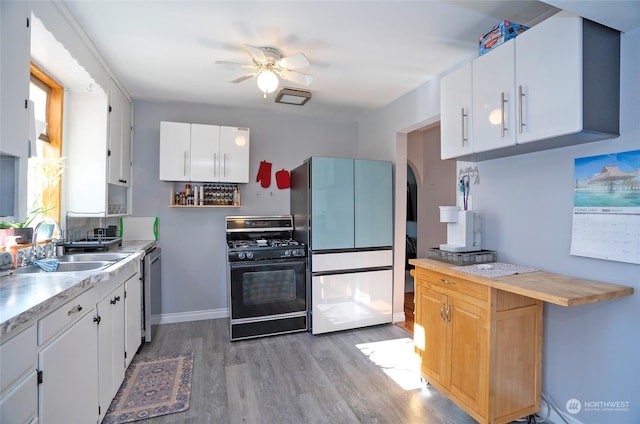 kitchen with hardwood / wood-style floors, refrigerator, white cabinets, stainless steel dishwasher, and black range with gas cooktop