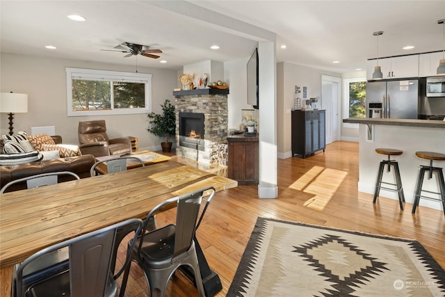 living room featuring a fireplace, light hardwood / wood-style flooring, and ceiling fan