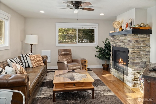 living room featuring a fireplace, wood-type flooring, and ceiling fan