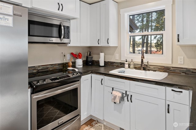 kitchen with appliances with stainless steel finishes, sink, and white cabinets