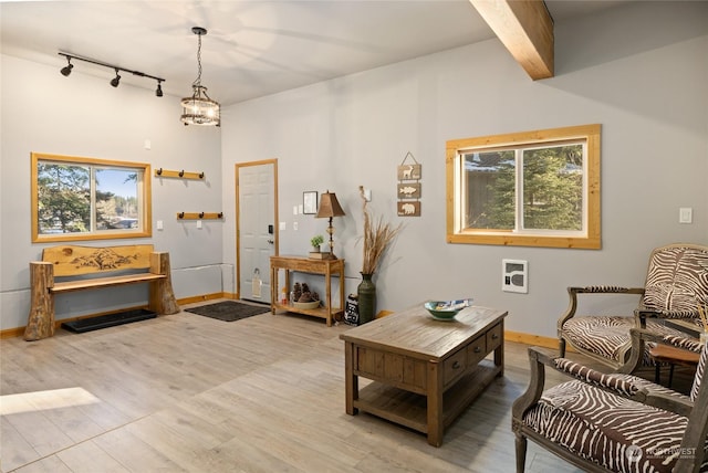 interior space featuring beamed ceiling, track lighting, an inviting chandelier, and light wood-type flooring