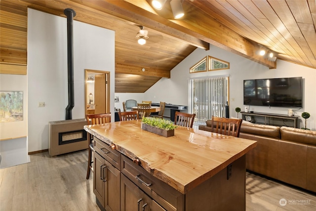 kitchen with a center island, lofted ceiling with beams, light hardwood / wood-style flooring, wooden ceiling, and a wood stove