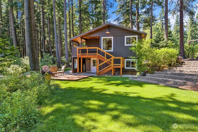 rear view of property featuring a wooden deck, a yard, and a patio area