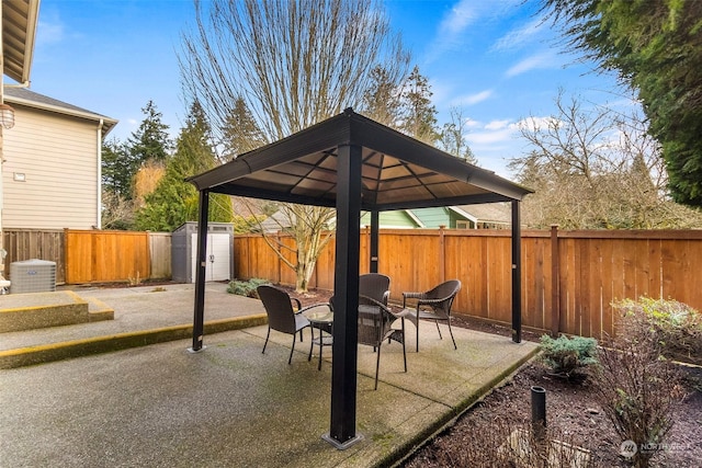 view of patio / terrace with a gazebo, a fenced backyard, a storage unit, and an outdoor structure