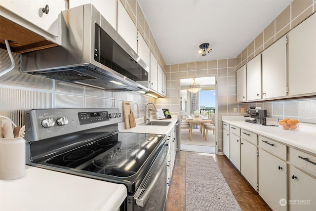 kitchen featuring stainless steel appliances, white cabinetry, sink, and backsplash