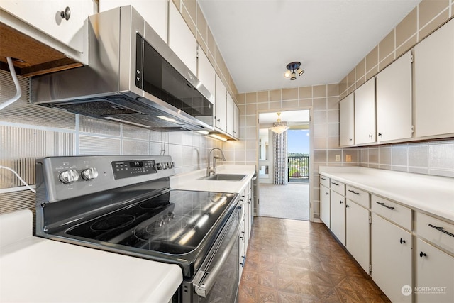 kitchen featuring dark parquet floors, sink, white cabinets, decorative backsplash, and stainless steel appliances