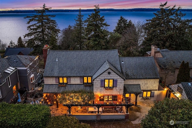 back house at dusk featuring a patio and a water view