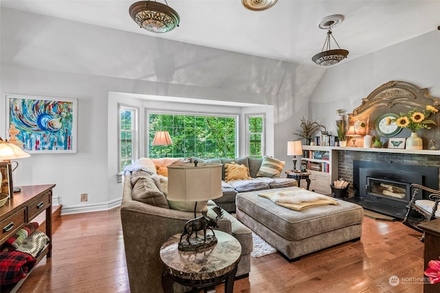 living room with lofted ceiling, a brick fireplace, and wood-type flooring