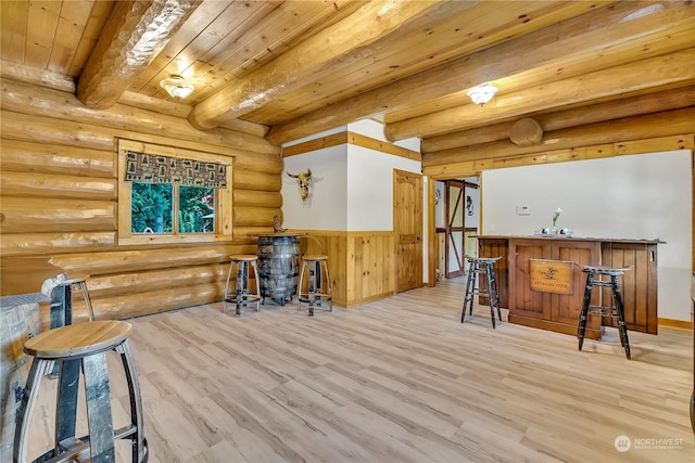 interior space featuring rustic walls, wooden ceiling, wet bar, beamed ceiling, and light hardwood / wood-style floors