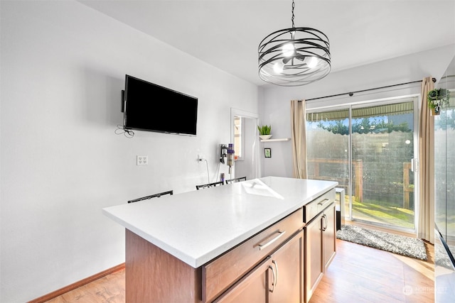 kitchen with pendant lighting, an inviting chandelier, a kitchen island, and light wood-type flooring