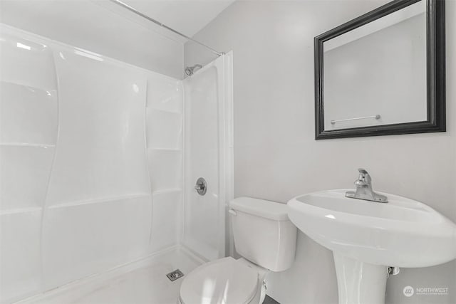 bathroom with sink, a shower, and toilet