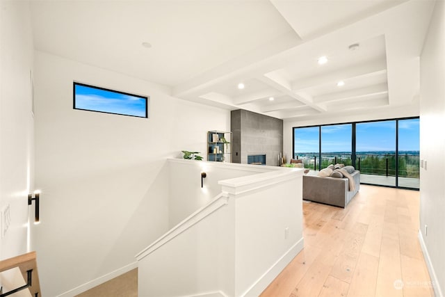 hall featuring coffered ceiling, beam ceiling, floor to ceiling windows, and light wood-type flooring