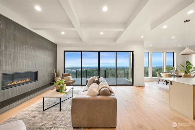 living room featuring coffered ceiling, beam ceiling, a tile fireplace, and light hardwood / wood-style flooring