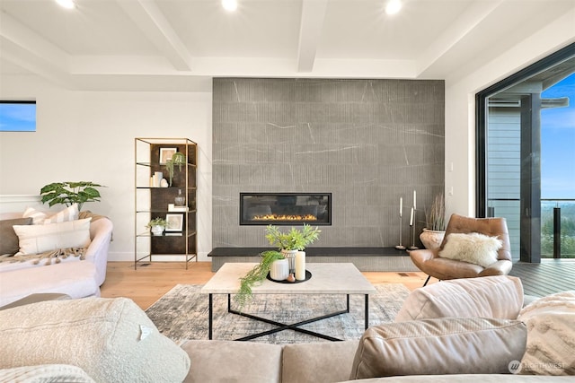 living room with beam ceiling, a fireplace, and light hardwood / wood-style flooring